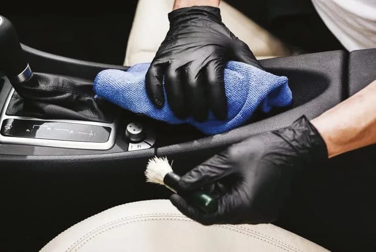 Siyah eldivenle orta konsolun mikrofiber bezle silinmesi